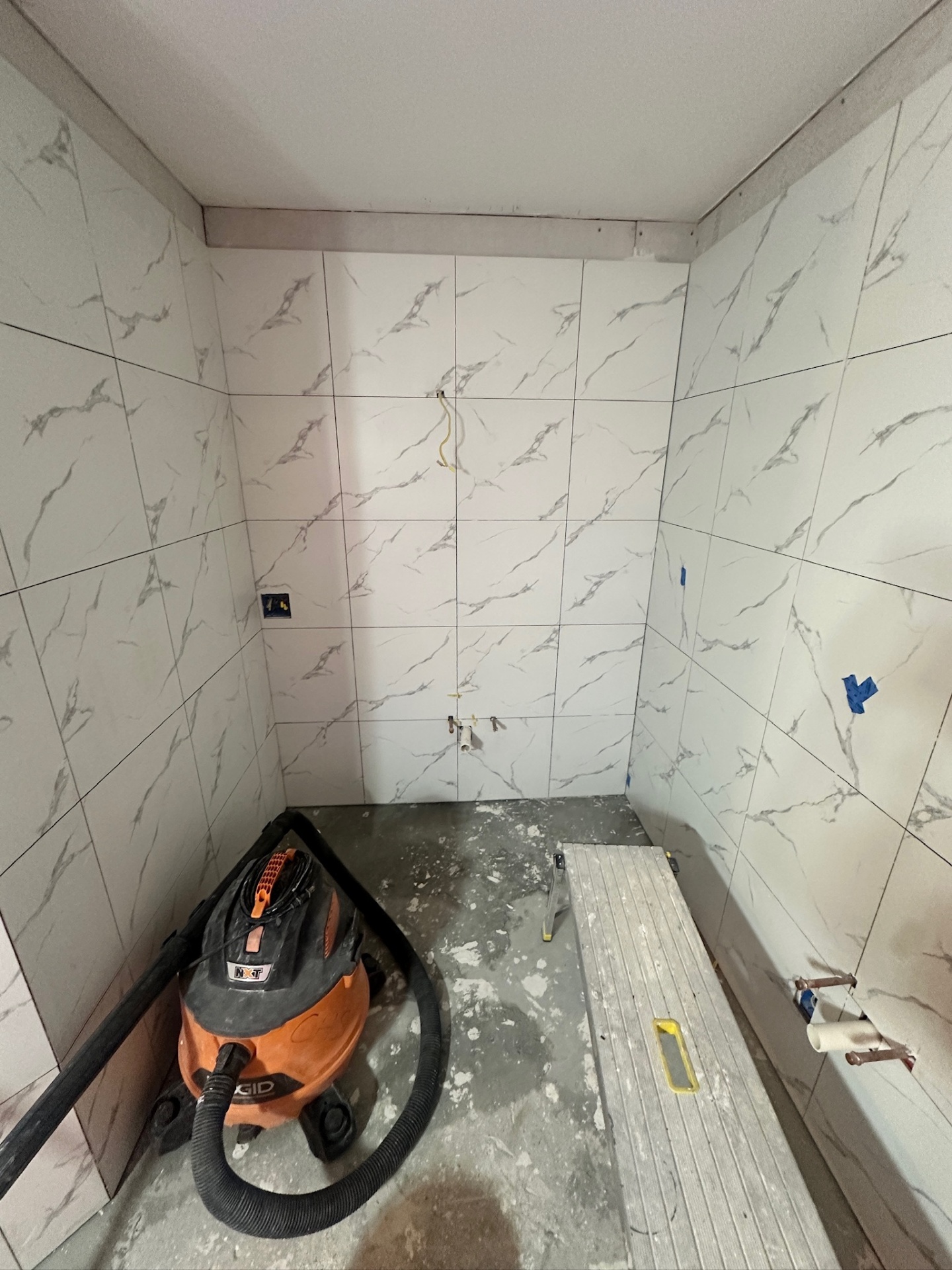 Water closet alcove fully tiled in marble-look porcelain with toilet supply stub ready in Metairie master bath