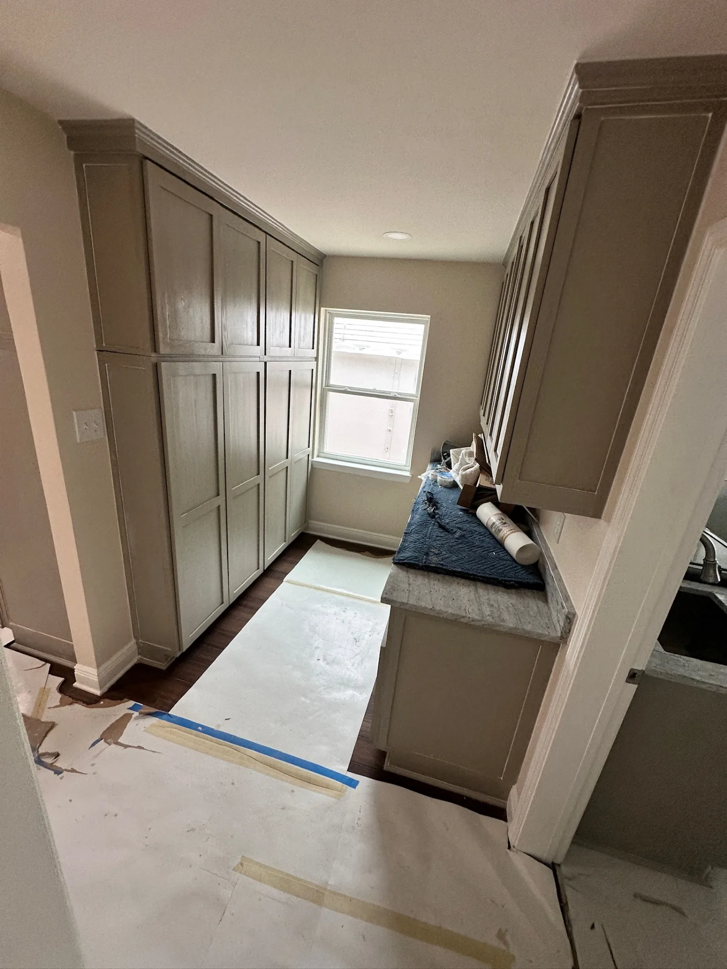 Finished butler pantry at Blanke Street Metairie home with floor-to-ceiling gray-stained shaker cabinetry, granite counter, and hardwood floor