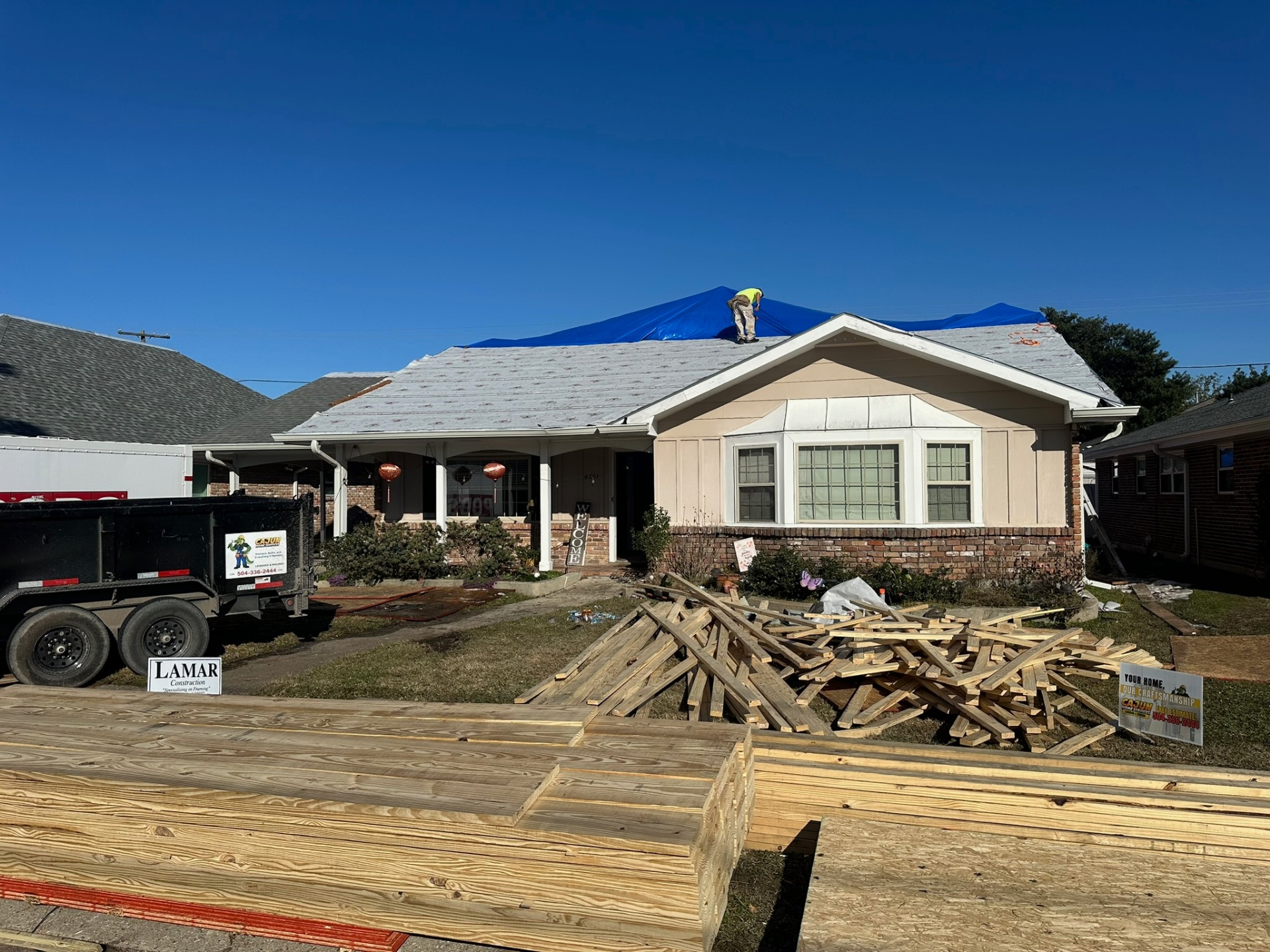 Front elevation of Metairie home addition with new second-floor decking installed and tarp protection in place