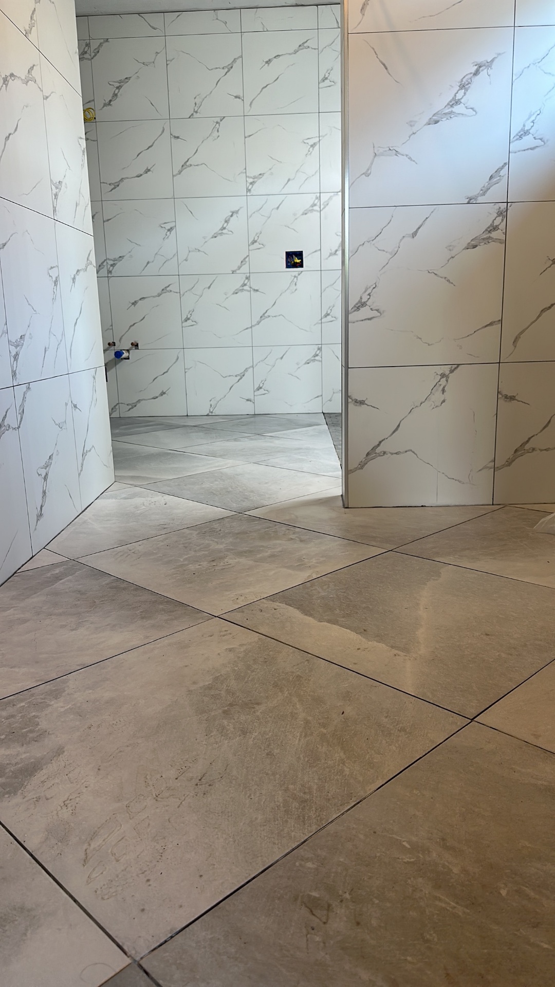 Large-format gray porcelain floor tile set on the diagonal at the entry to Metairie master bath
