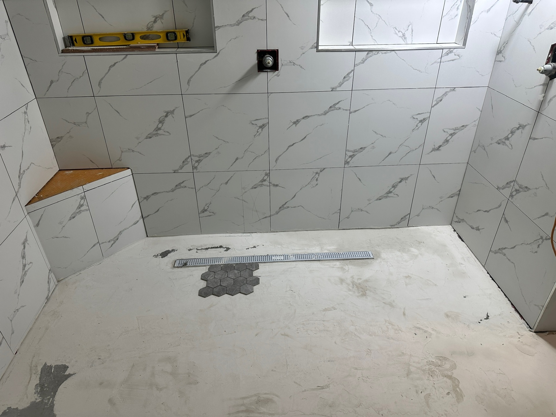 Linear shower drain set with hex mosaic dry-fit mockup on the prepped shower floor in Metairie master bath