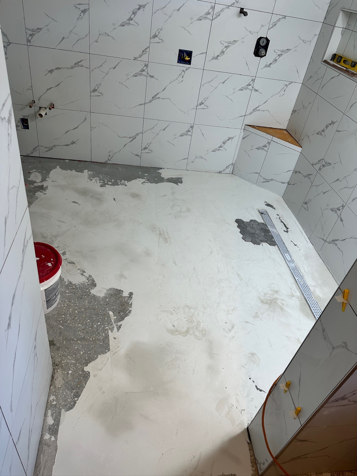 Main bathroom floor prepped with self-leveler and hex mosaic dry-fit at the shower drain in Metairie master bath