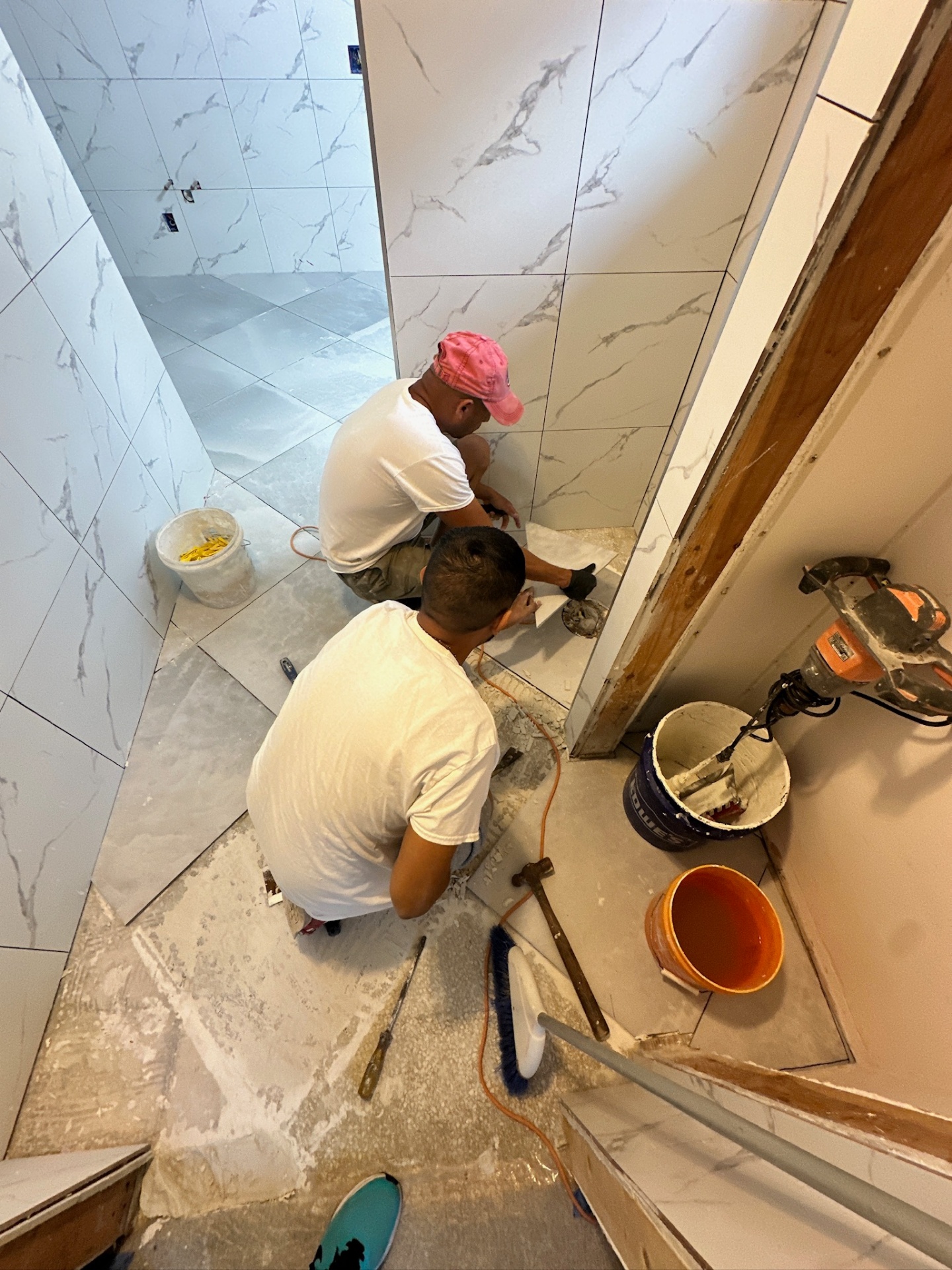 Cajun Home Services tile crew cutting and setting marble-look porcelain around the doorway in Metairie master bath
