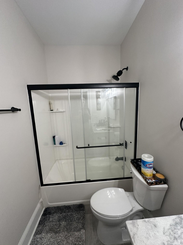 Finished framed sliding glass tub door with matte black frame and hardware in Meraux Louisiana bathroom renovation with white subway shower walls