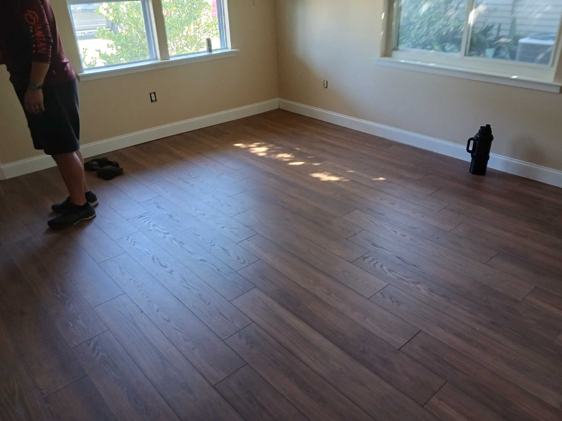 Finished bedroom in the rebuilt Gretna home with new laminate flooring, fresh paint, and clean white baseboards