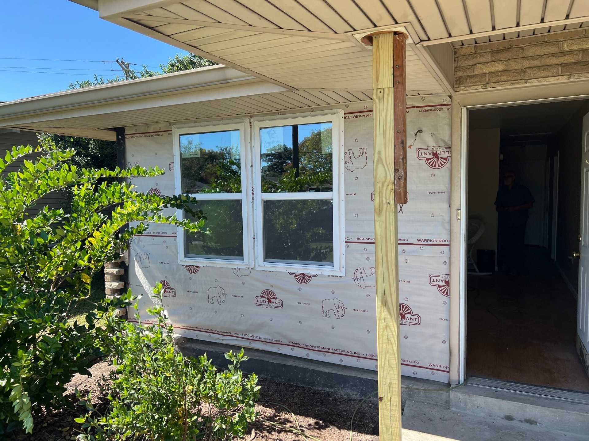 New white vinyl double-hung windows installed in the rebuilt front wall of the Gretna home with house wrap still exposed