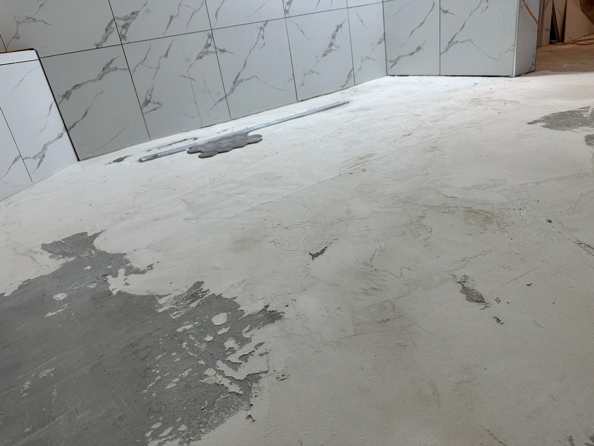Self-leveling compound poured across main bathroom floor after tile walls in Metairie master bath