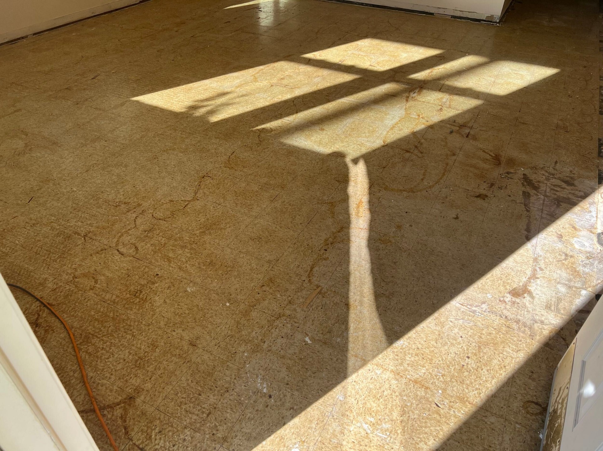 Old vinyl composition tile removed down to the original subfloor in the Gretna home during flooring replacement