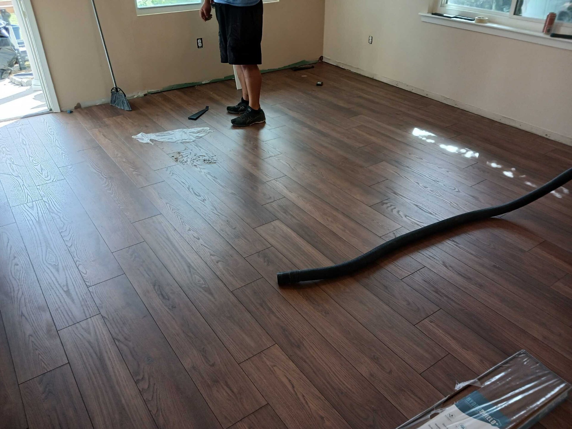 New wood-look laminate flooring installed across the Gretna living room during finish walkthrough with the installer on site