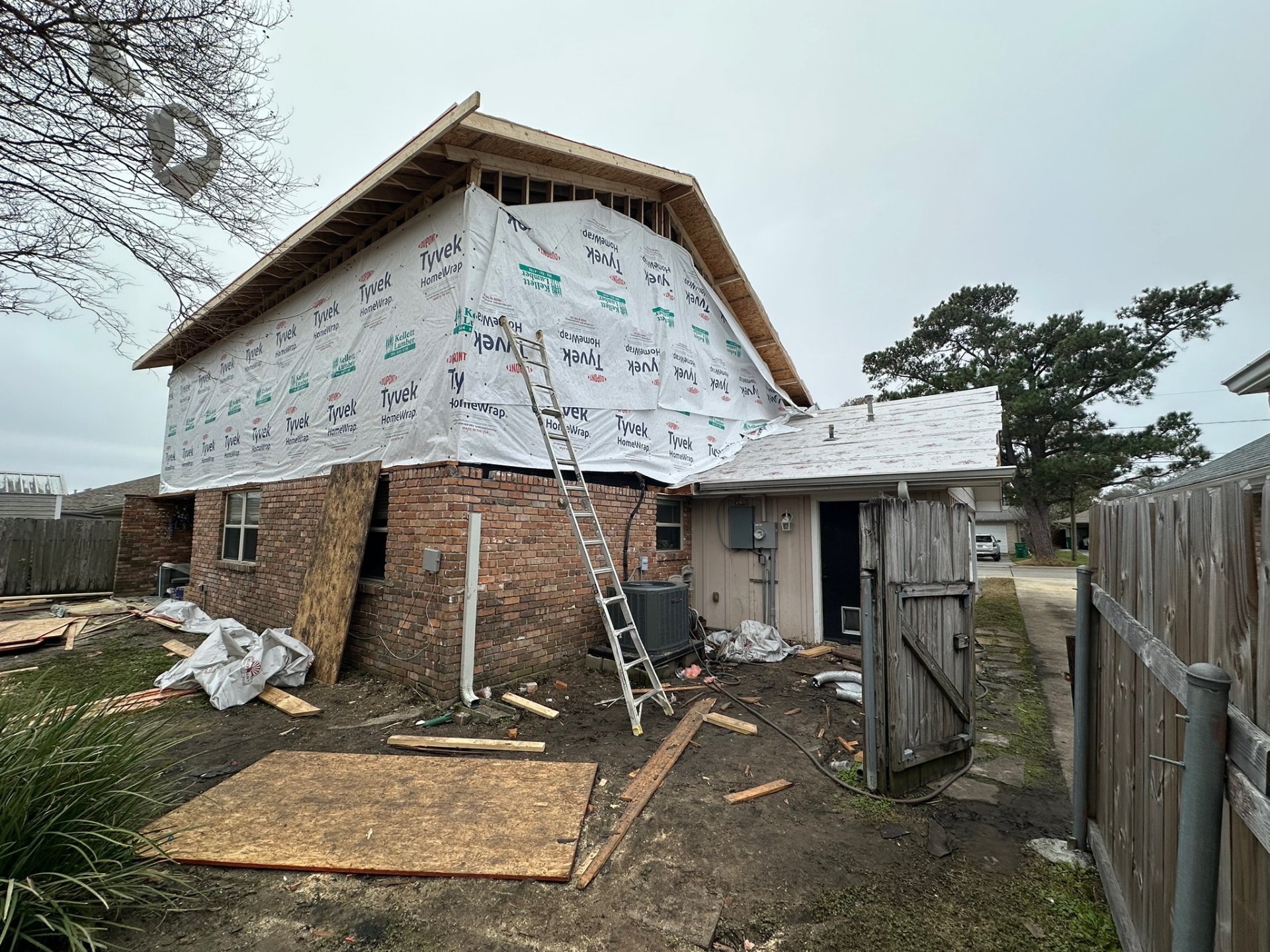 Rear corner of Metairie second-floor addition fully wrapped in Tyvek with new roof decking visible at the eaves