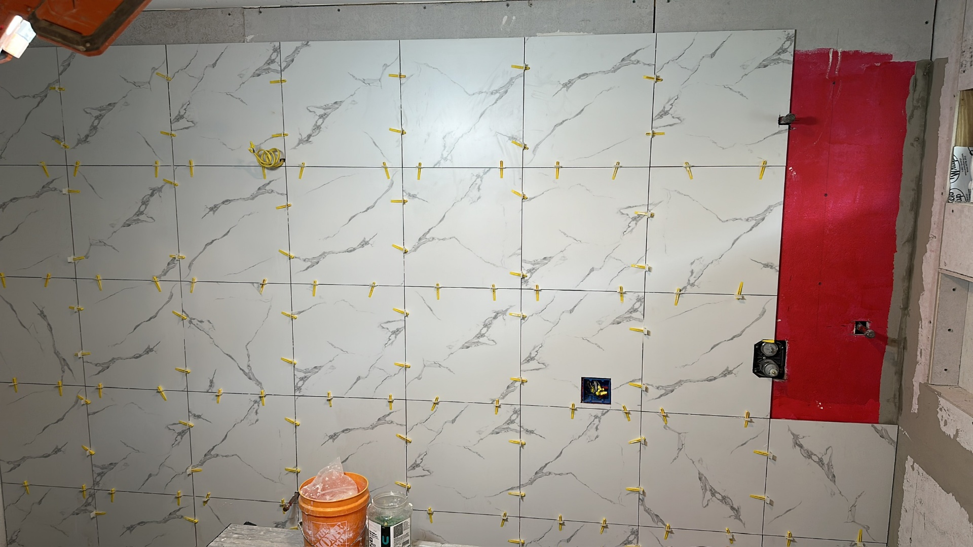 Book-matched marble-look porcelain tile pattern coming together on the shower wall in Metairie master bath