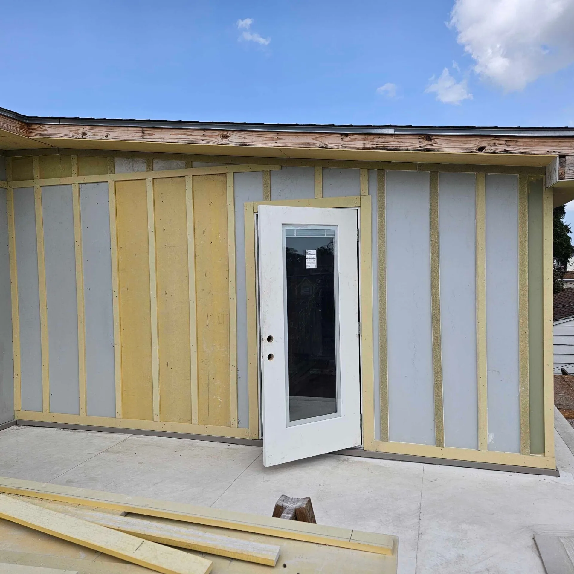 New exterior single-lite door installed on the second-story addition at Blanke Street Metairie home with primed board-and-batten siding around the opening