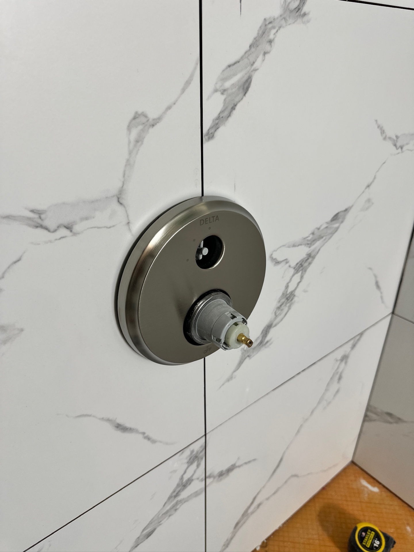 Delta round shower valve trim installed on marble-look tile in Metairie master bath