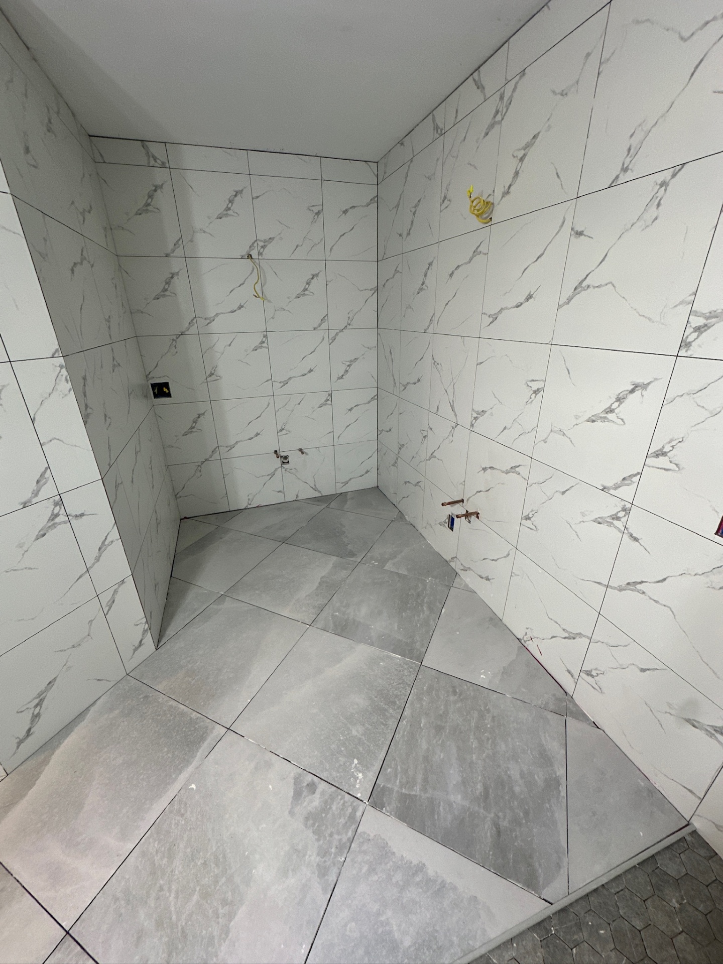 Water closet fully tiled with marble-look walls and diagonal porcelain floor in Metairie master bath
