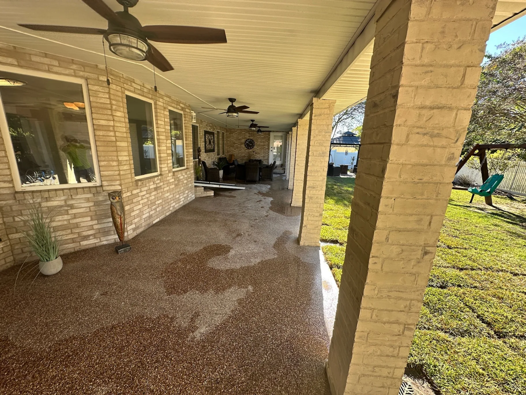Finished interior view of rebuilt covered patio at Destrehan Louisiana home with new vinyl soffit, ceiling fans, and limewashed brick posts by Cajun Home Services