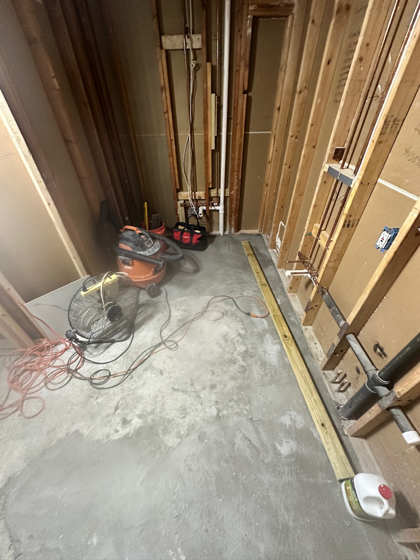 Slab patched and toilet drain roughed in behind new stud wall in Metairie master bath