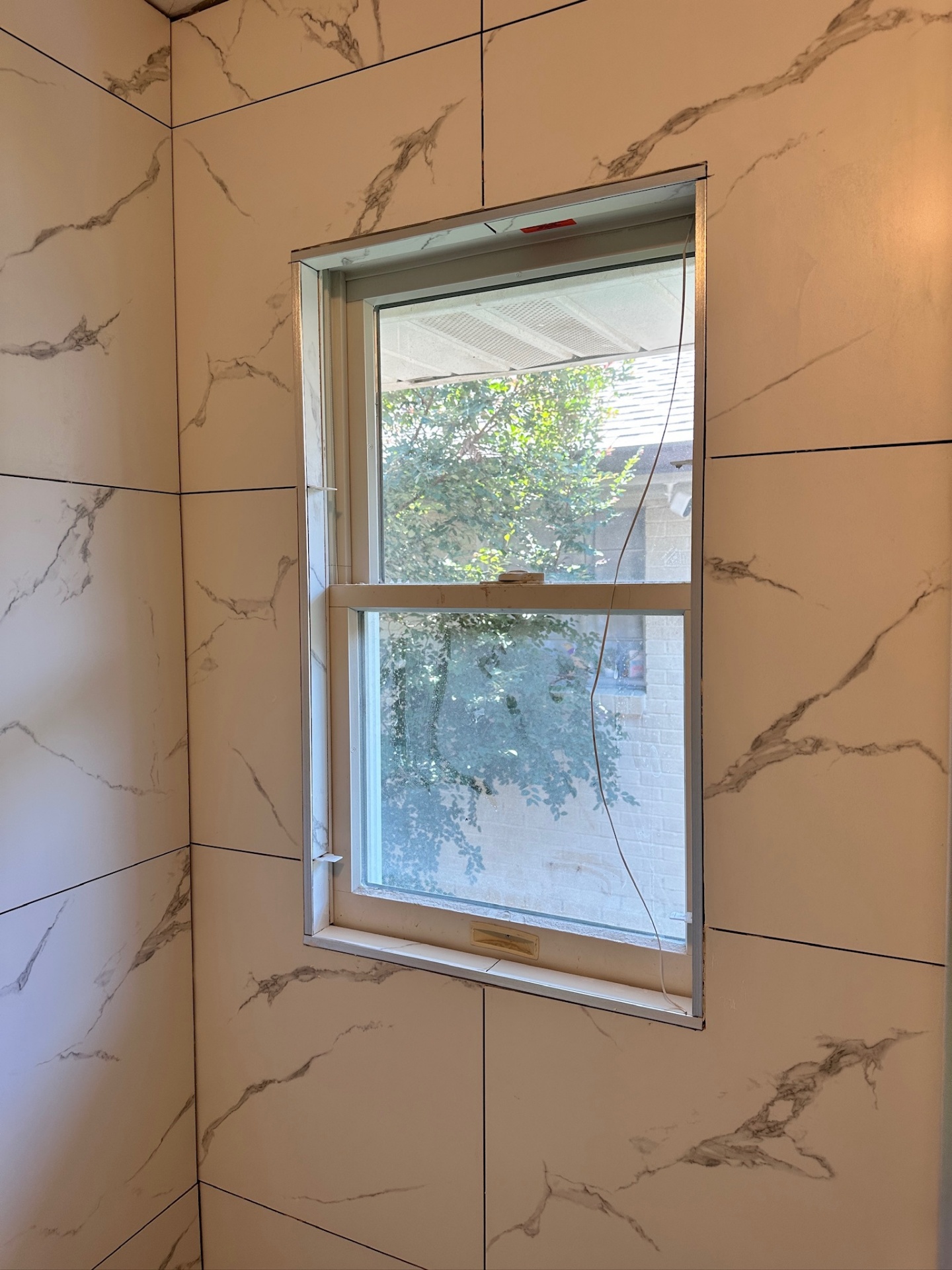 Bedroom window wrapped in marble-look porcelain with Schluter Jolly edge trim in Metairie master bath