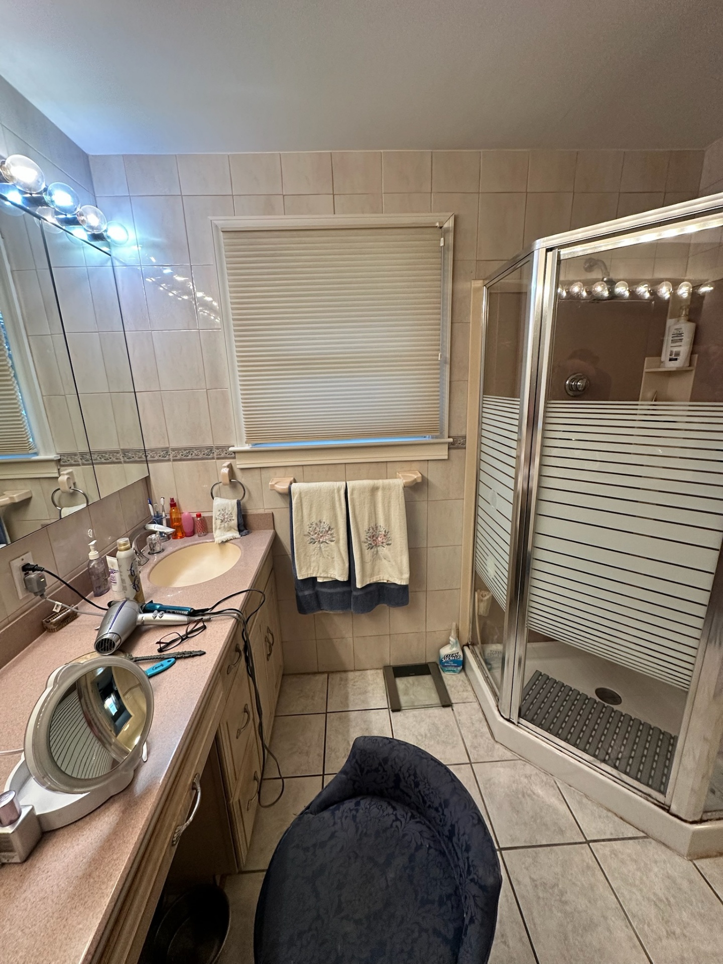 Before — dated peach vanity and neo-angle glass shower stall in Metairie master bath