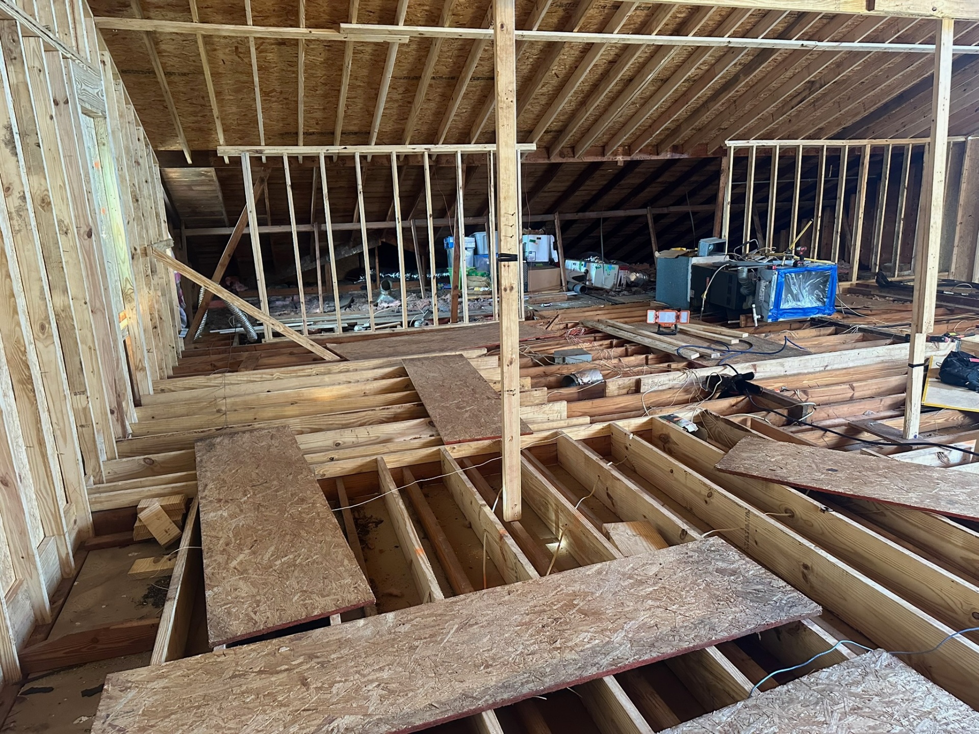 Inside Metairie second-floor framing with new knee walls standing in front of existing attic mechanical equipment and ductwork tucked behind the new wall line