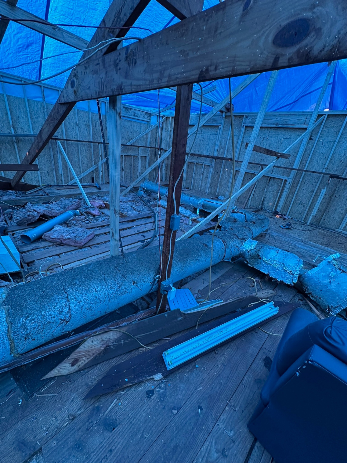 Existing roof torn off Metairie home with tarp suspended overhead protecting interior during second-floor addition