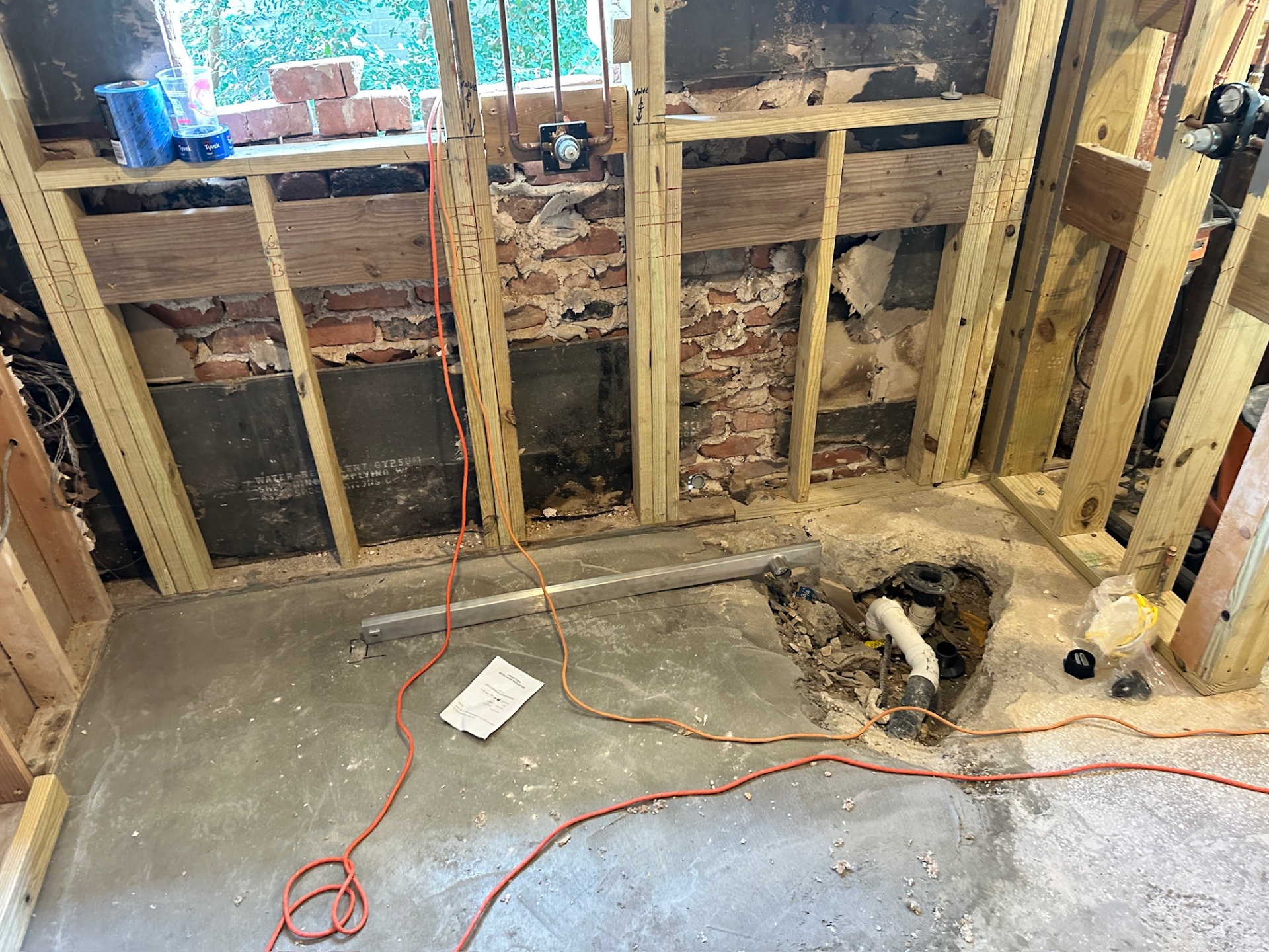 Slab opened at old tub drain with new stud walls and rerouted plumbing in Metairie master bath