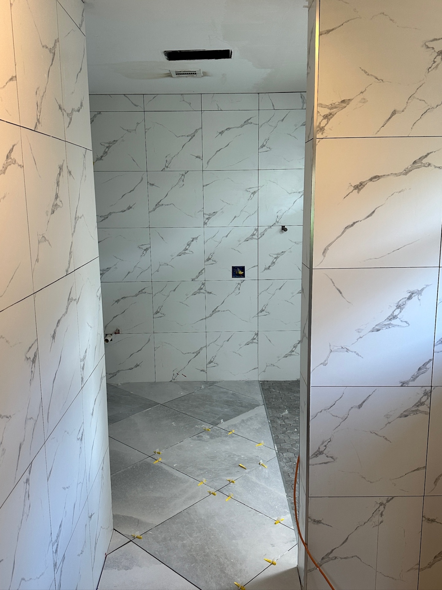 Water closet alcove with floor tile leveling clips set on the diagonal in Metairie master bath