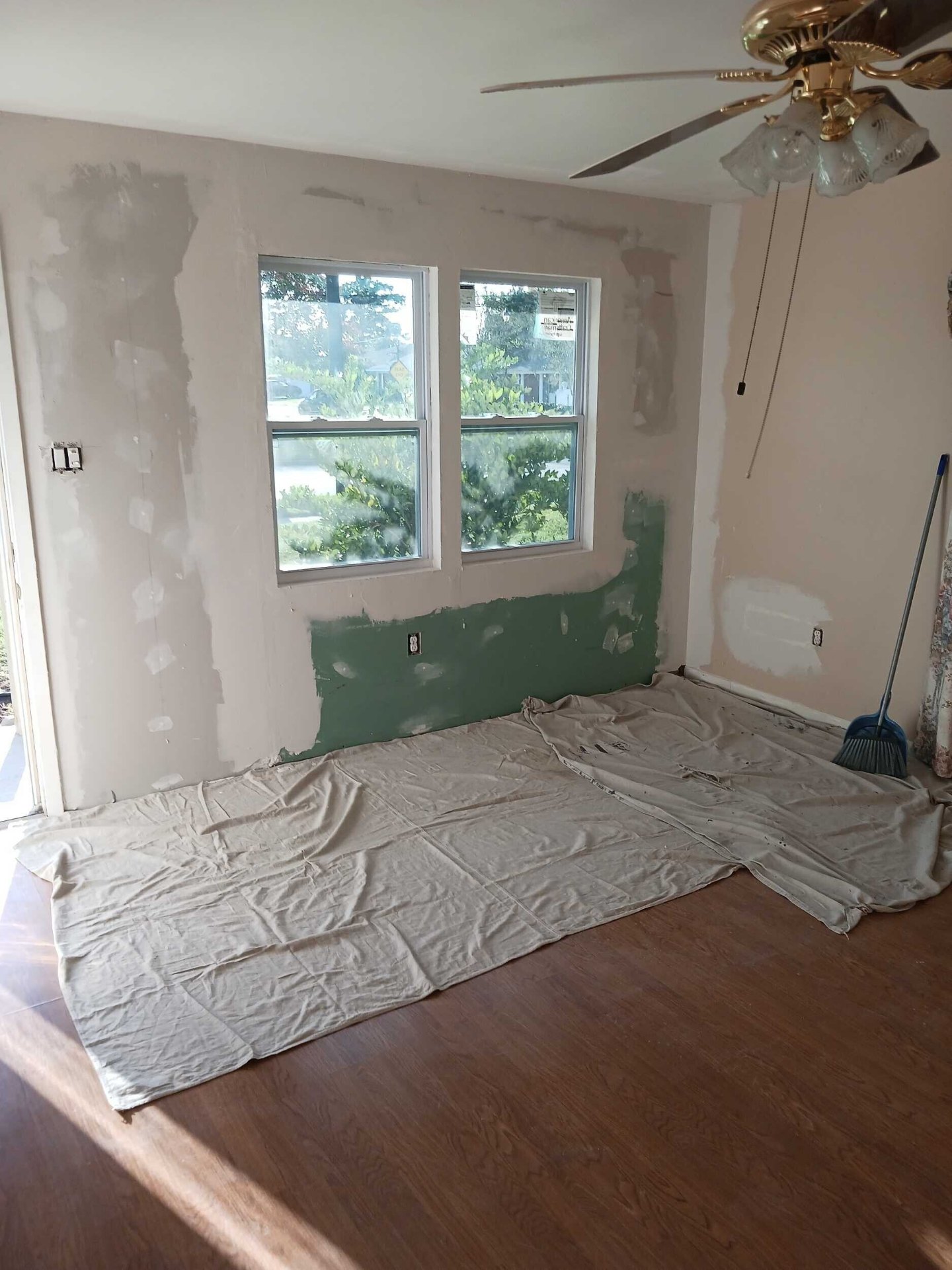 Interior wall with drywall patches primed around the new windows in the Gretna rebuild, drop cloth on the floor ready for finish paint