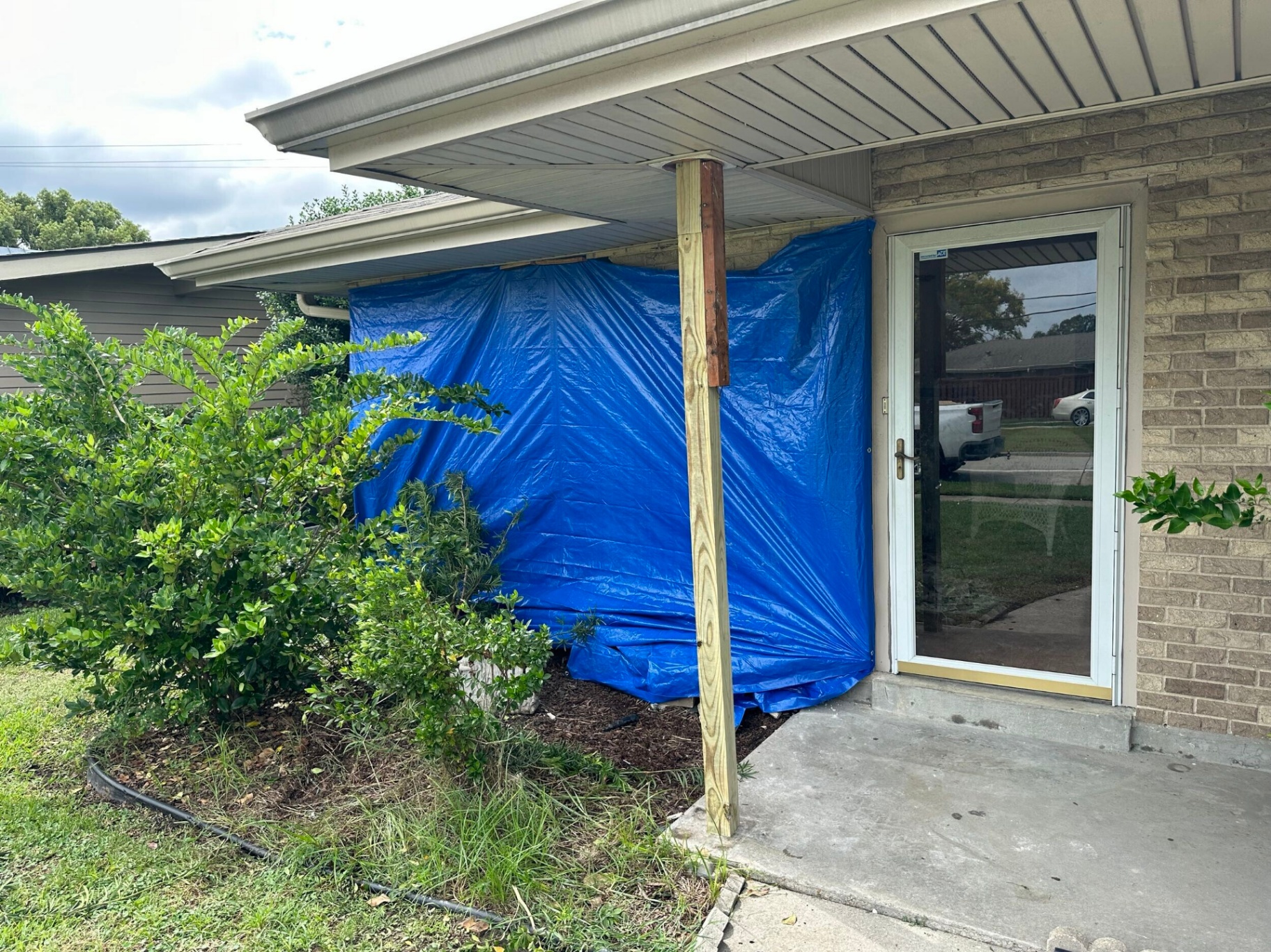 Blue emergency tarp covering the damaged front wall of a Gretna home the morning after a vehicle impact