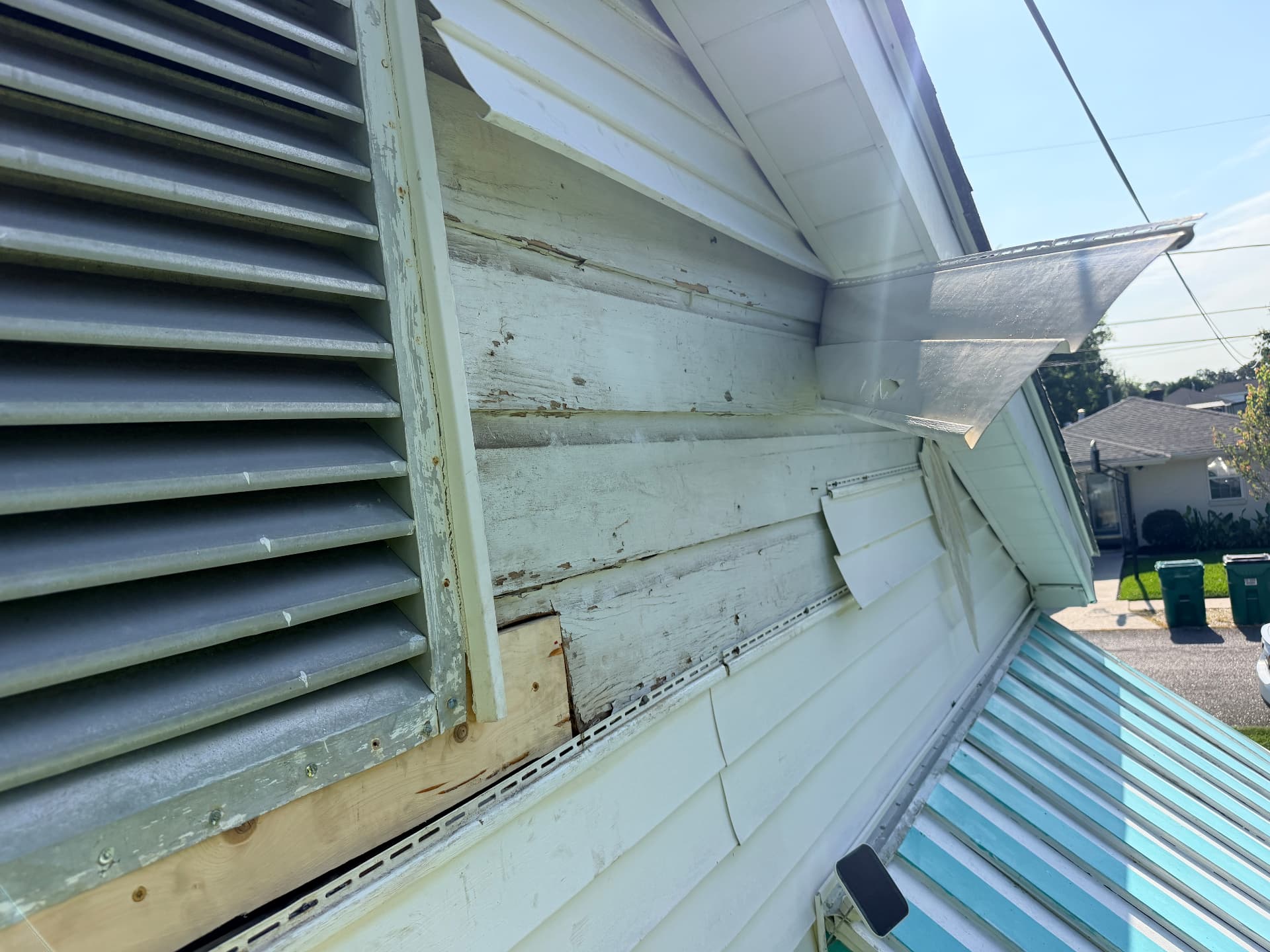 Detached vinyl siding exposing wood sheathing during Metairie gable vent repair