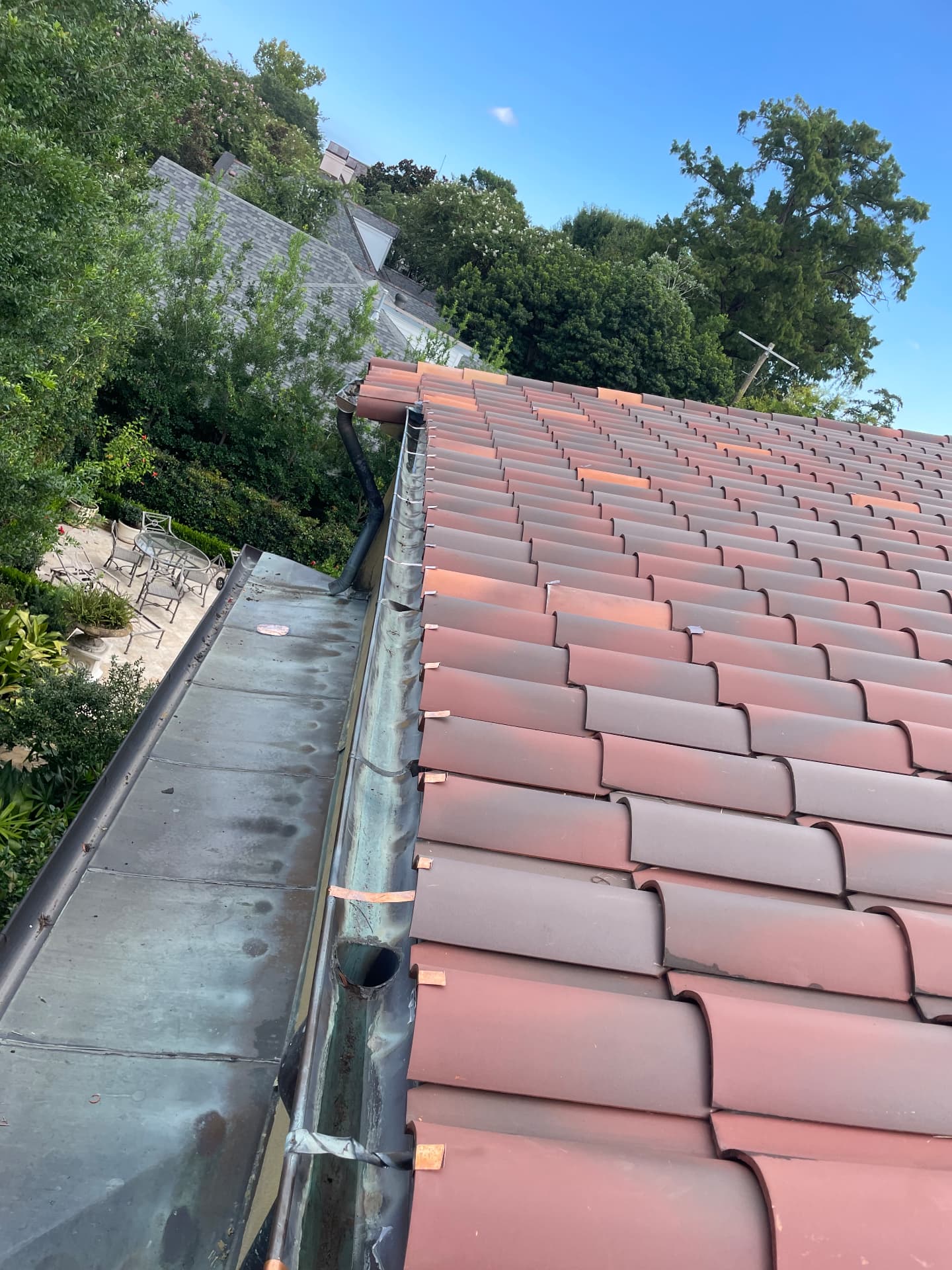 Completed terra cotta tile roof slope with repaired copper gutter and downspout in Metairie Louisiana