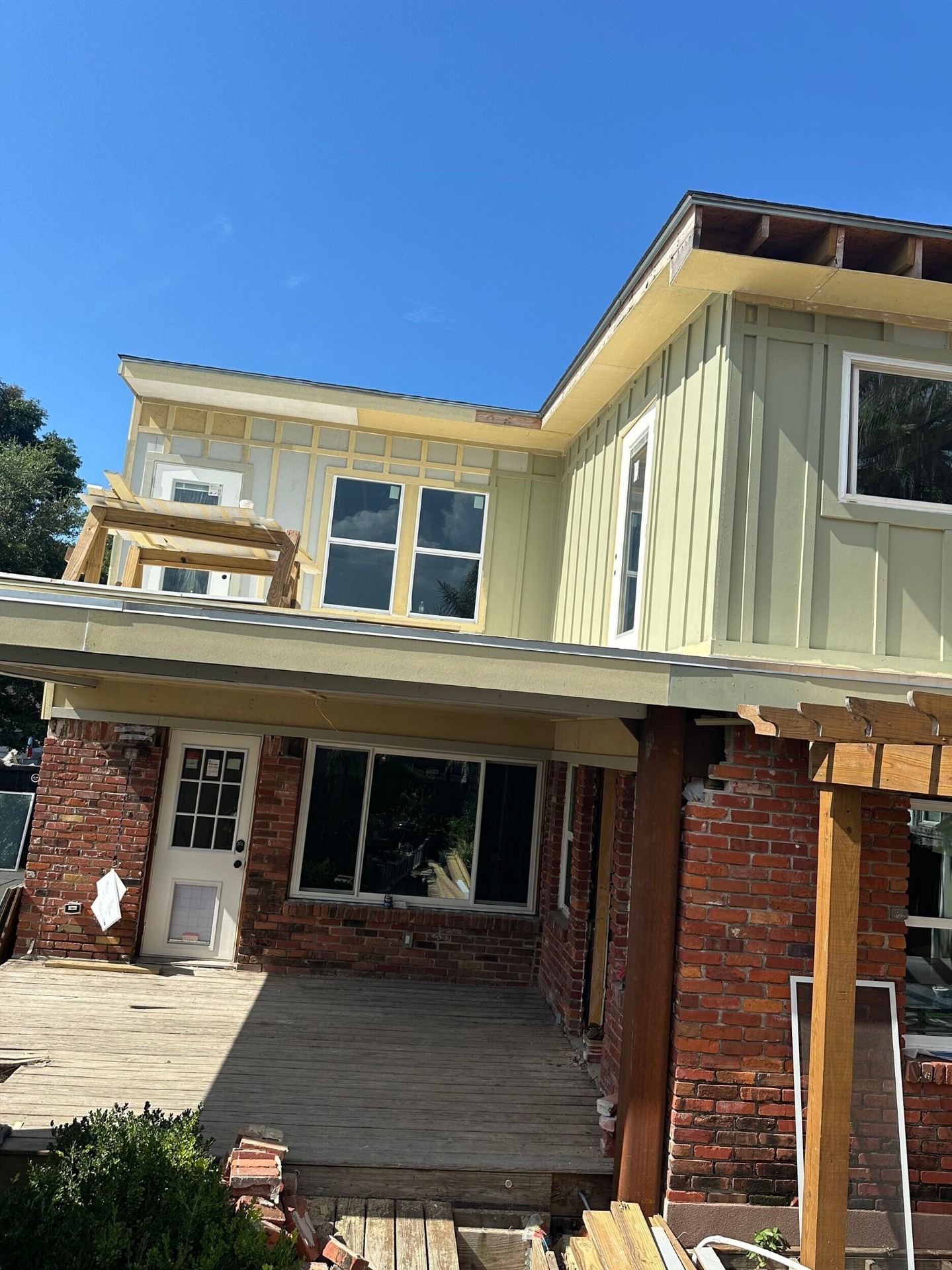 Rear elevation of Blanke Street Metairie home with siding progress on new second story over original brick first floor