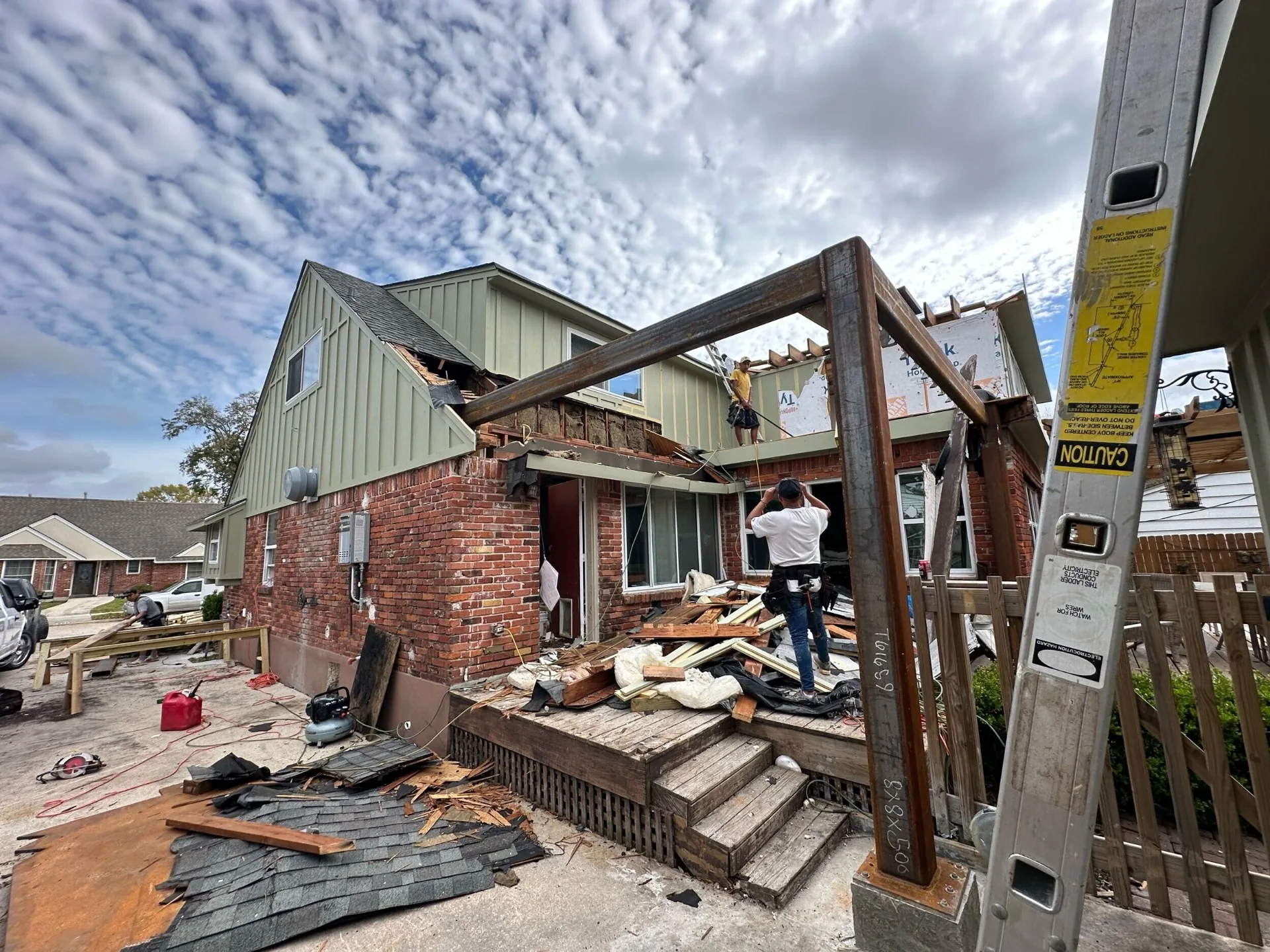 Side elevation of Blanke Street Metairie home during roof tear-off with new structural steel columns installed at the rear addition