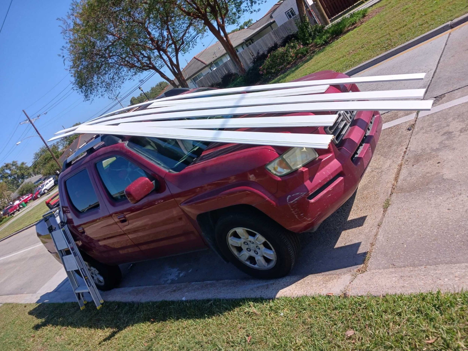 Cajun Home Services truck loaded with new white vinyl trim and J-channel staged in front of the Gretna home for exterior finish work
