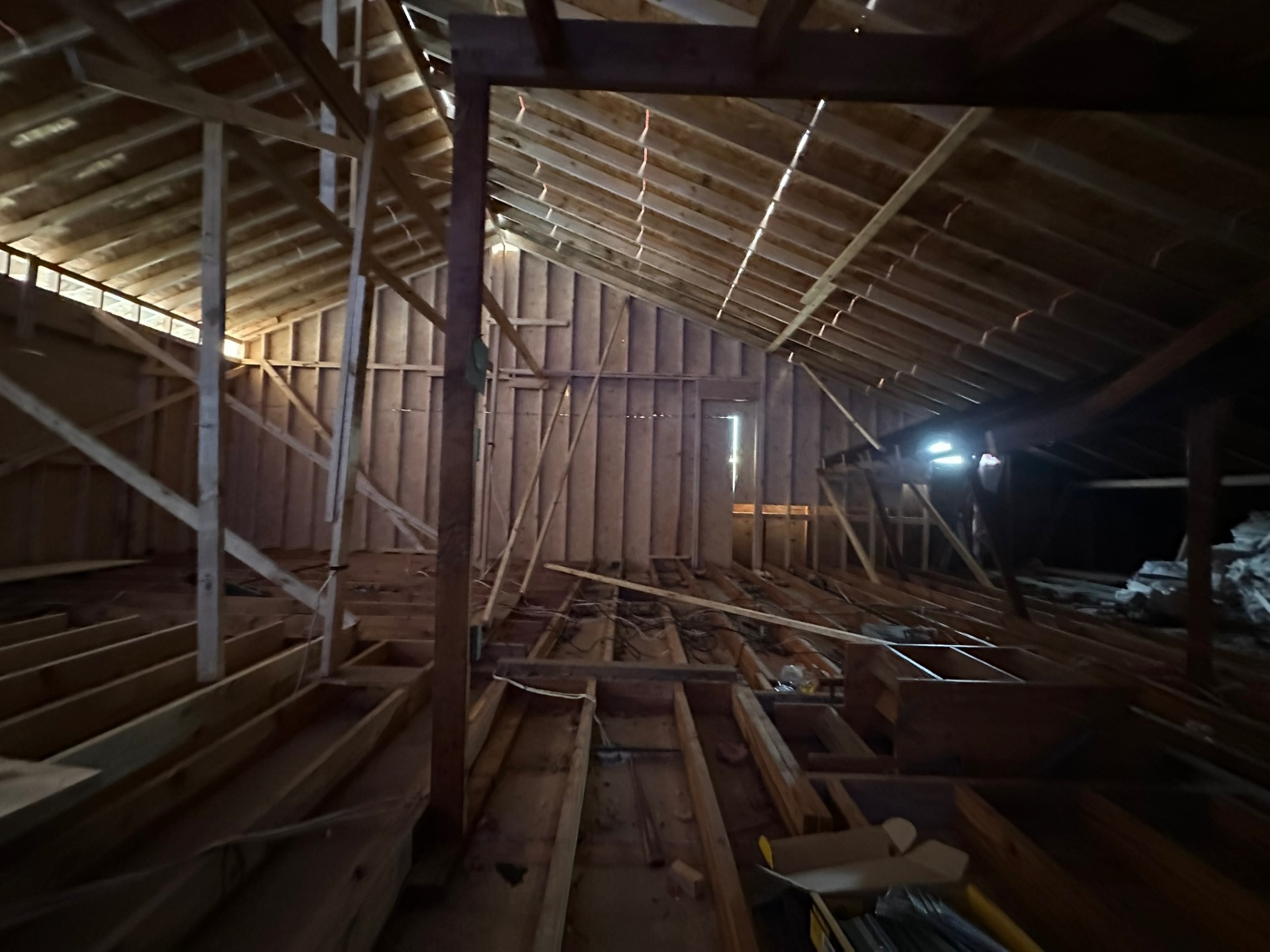 Wide interior view from new second floor of Metairie addition showing dark original rafters and new framing meeting