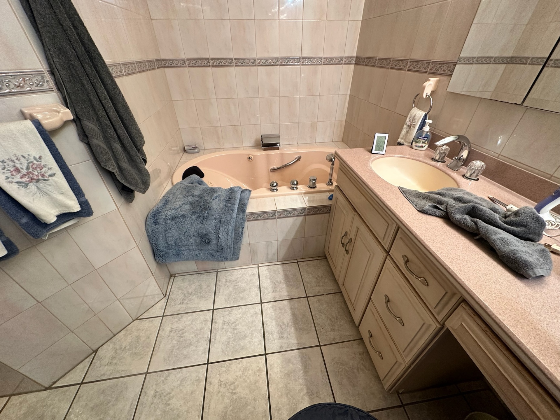 Before — peach jetted tub, laminate vanity top, and dated tile in Metairie master bath