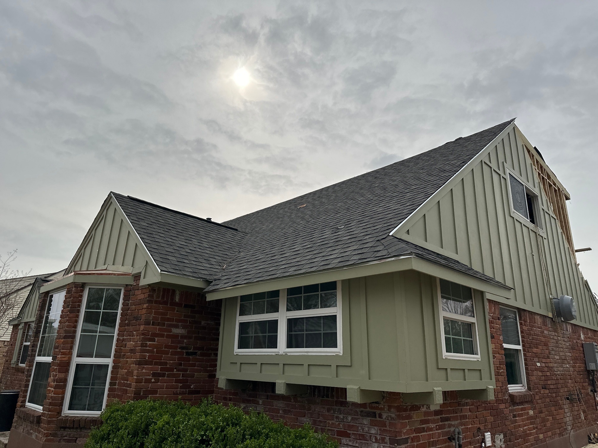 Finished exterior of Blanke Street Metairie home with new board and batten siding, matching shingle roof, and preserved brick base after Cajun Home Services whole-home remodel