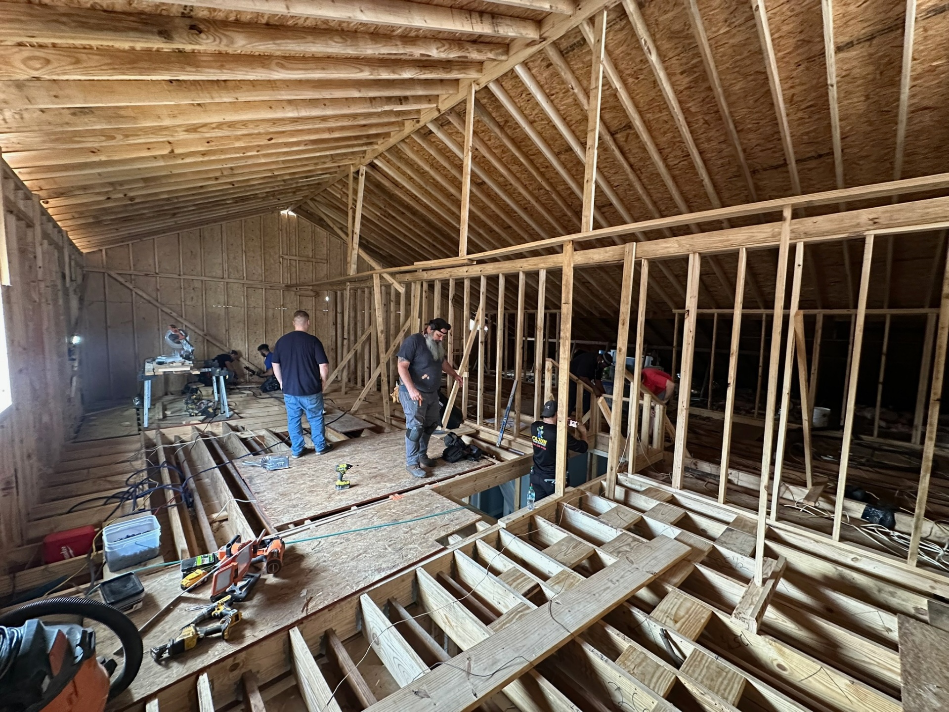 Wide interior view from inside Metairie second-floor addition with all exterior wall framing, knee walls and new roof rafters in place letting natural light flood the open space