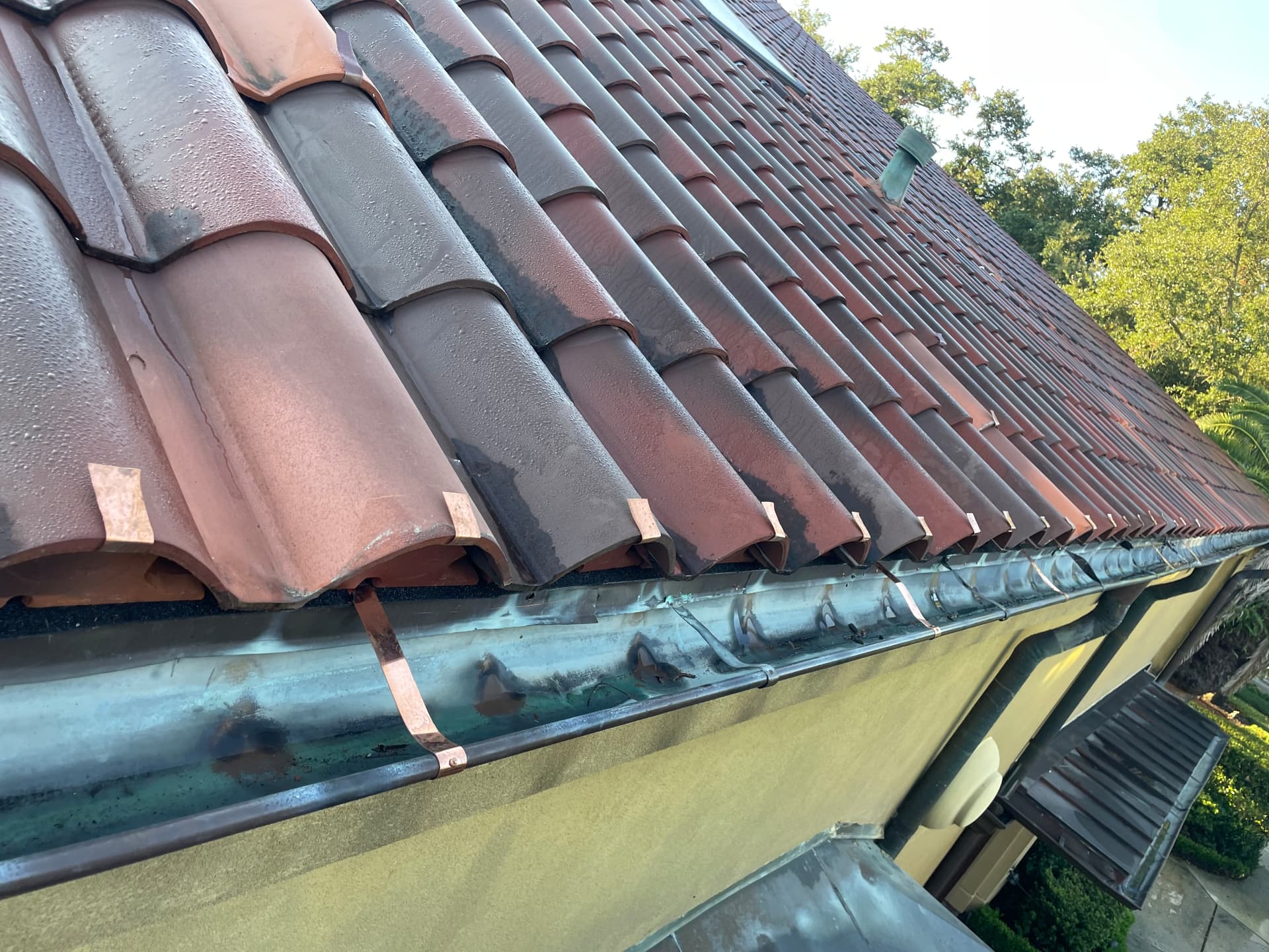 Finished terra cotta tile eave with new copper hanger straps securing the half round copper gutter in Metairie Louisiana