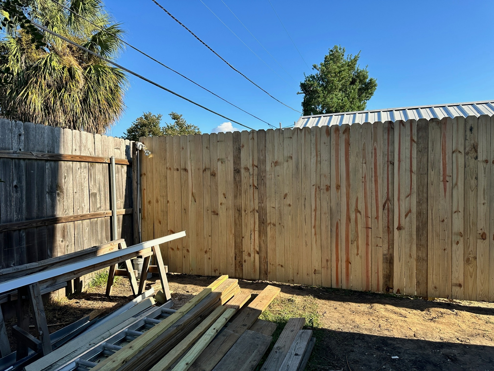 Back corner showing new picket fence next to old fence in Metairie Louisiana