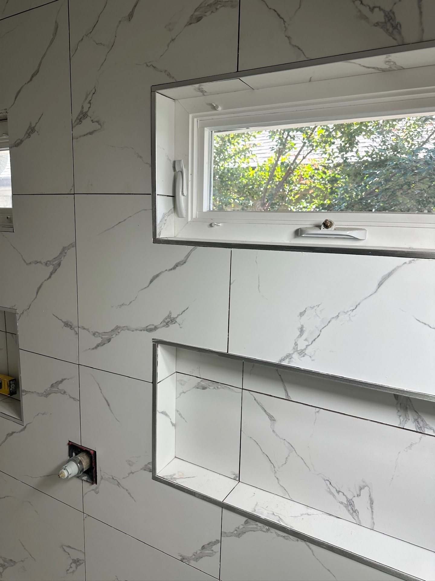 Schluter Jolly metal edge trim wrapping shower niche and awning window openings in Metairie master bath
