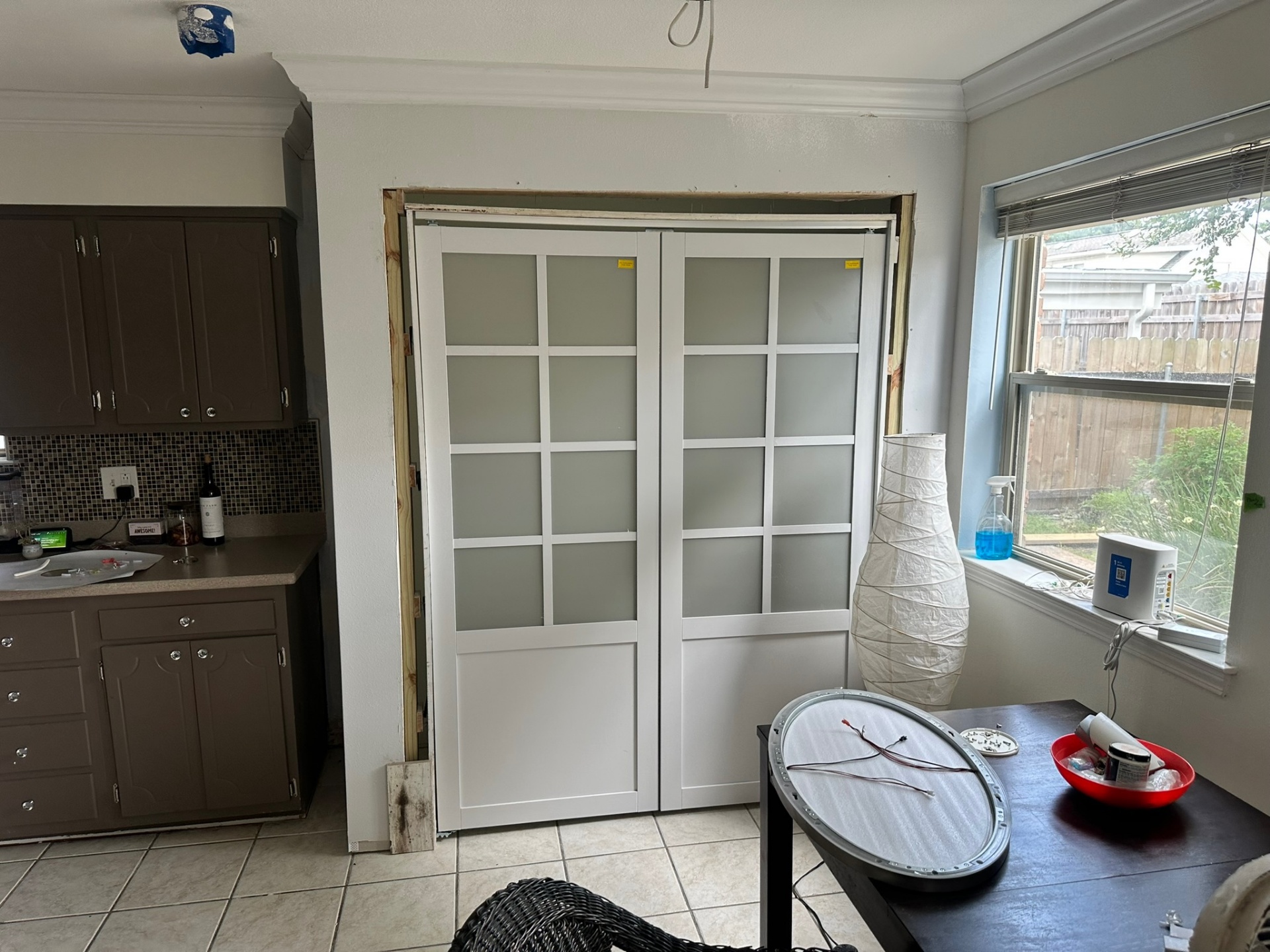 Interior view from the original first floor of the Metairie home with newly installed frosted double doors set in the opening below the second-floor addition, trim still off and tools staged during finish work