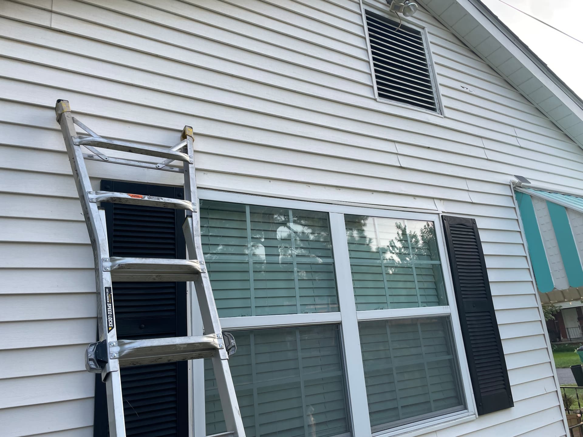 Before — Metairie home exterior with siding intact prior to gable vent leak repair