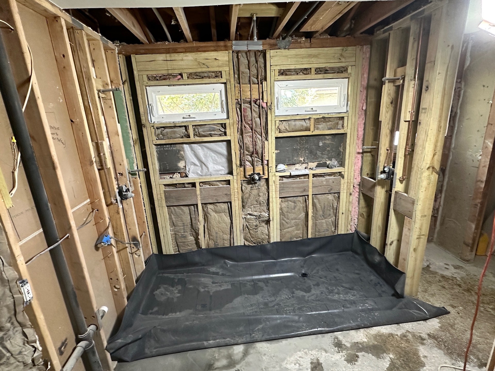 Wide view of finished shower pan liner and framed dual-window shower wall in Metairie master bath