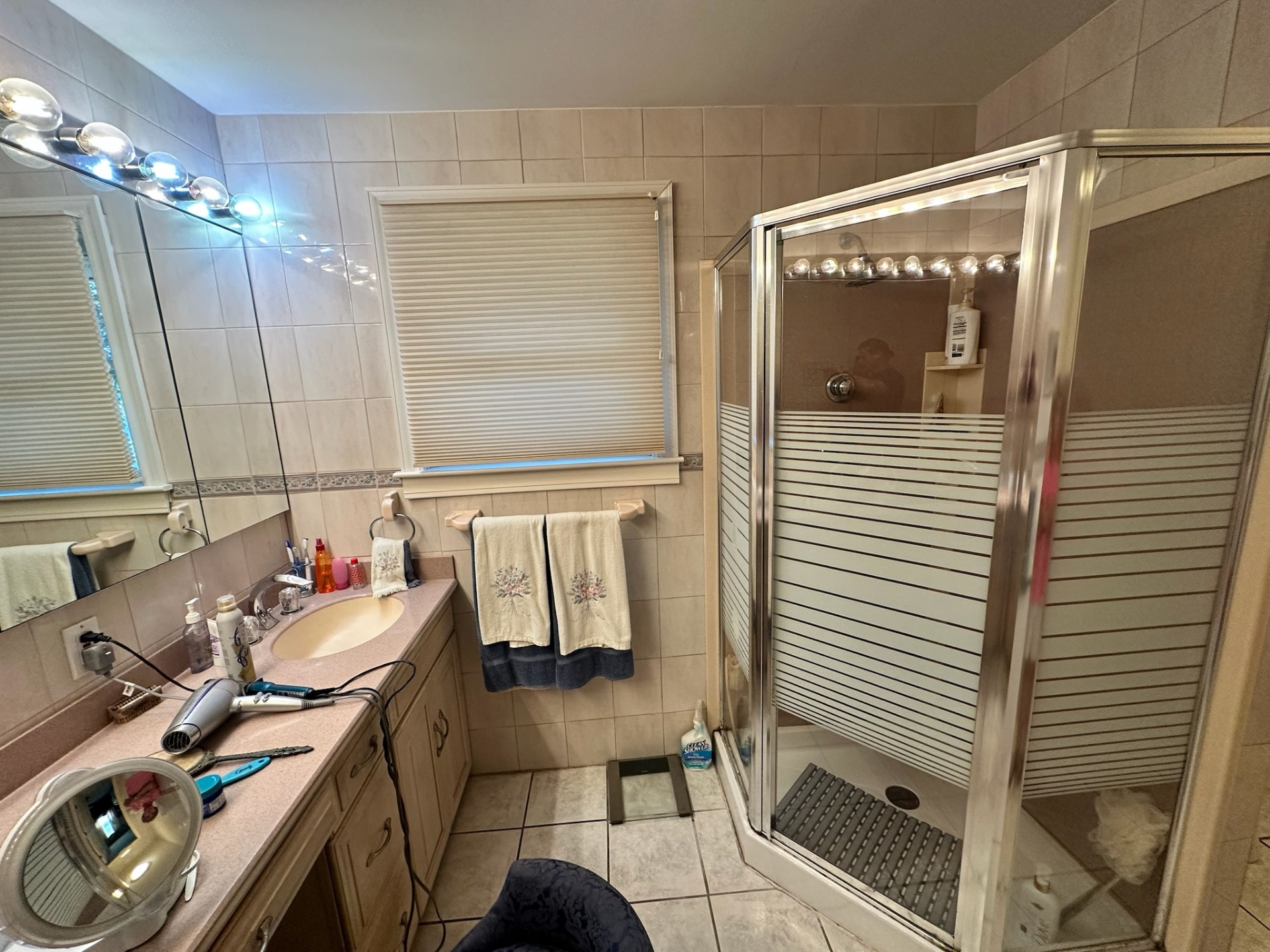 Before — dated glass shower stall with striped film and peach fixtures in Metairie master bath