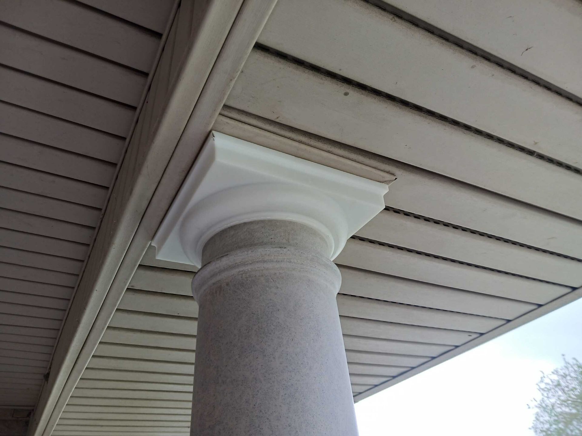 Detail of the finished white PVC column capital where the new porch column meets the vinyl soffit on the Gretna rebuild