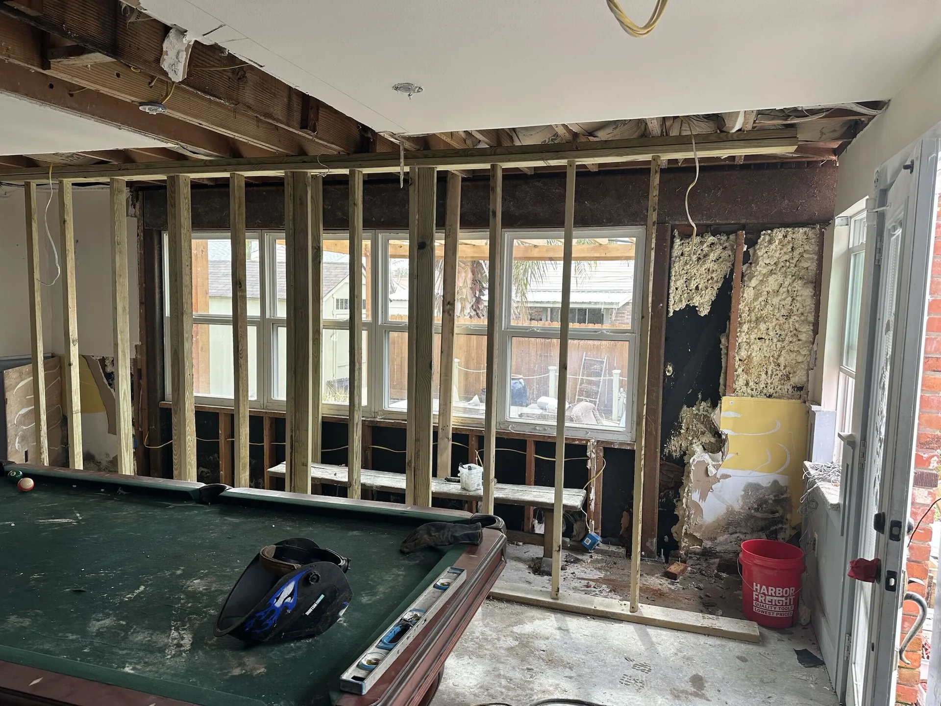 Close-up of new pressure-treated stud framing at the rear window wall of the Blanke Street Metairie remodel with existing brick veneer exposed