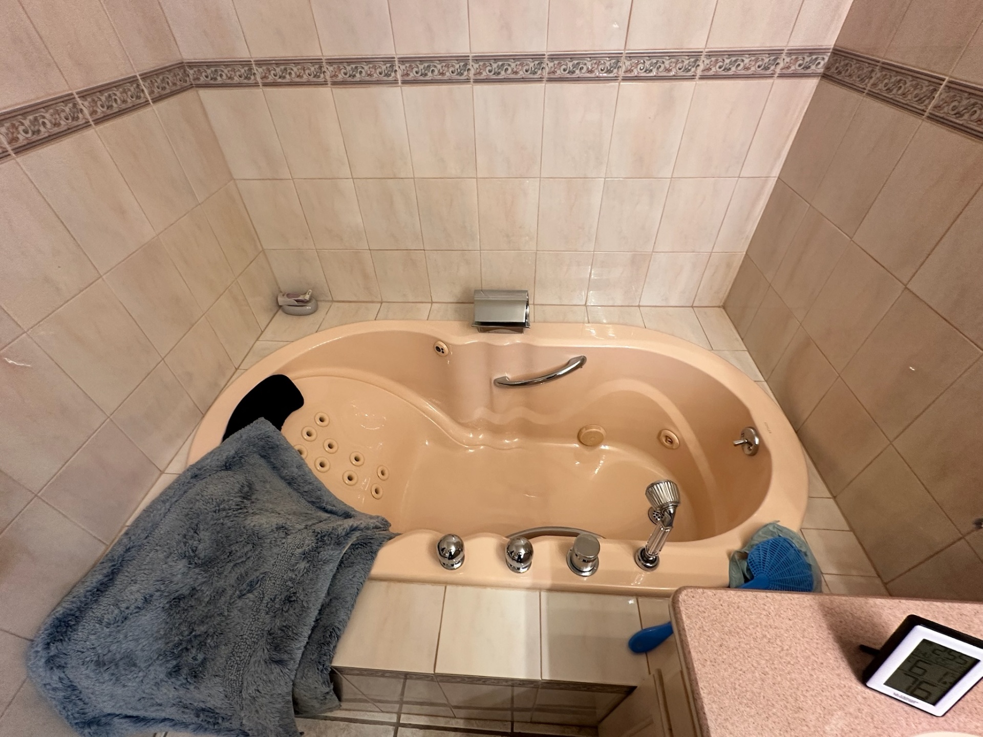 Before — peach jetted corner tub with dated floral border tile