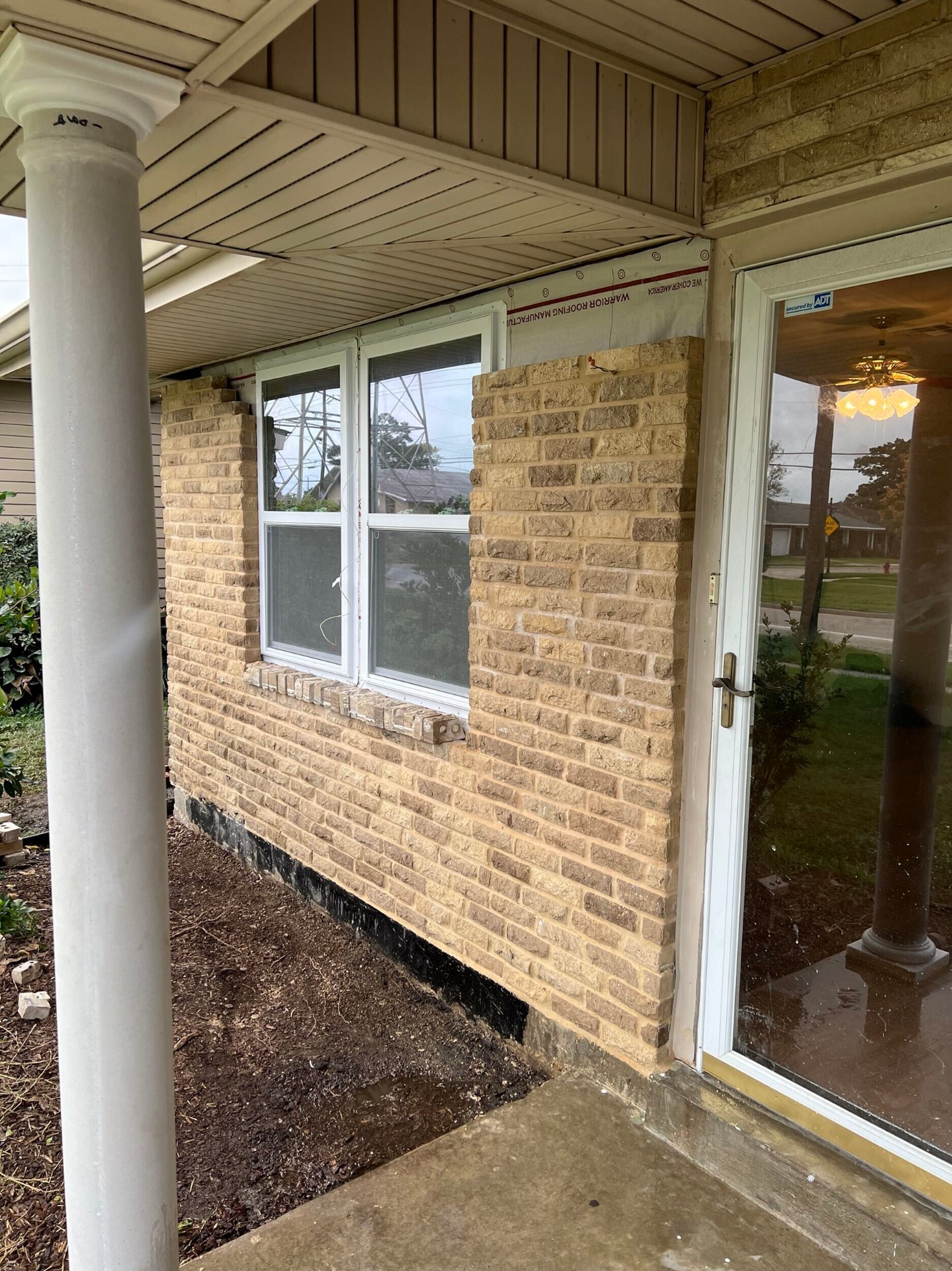 Rebuilt brick veneer wrapping into the porch column and front door of the Gretna home with clean mortar joints and color-matched brick