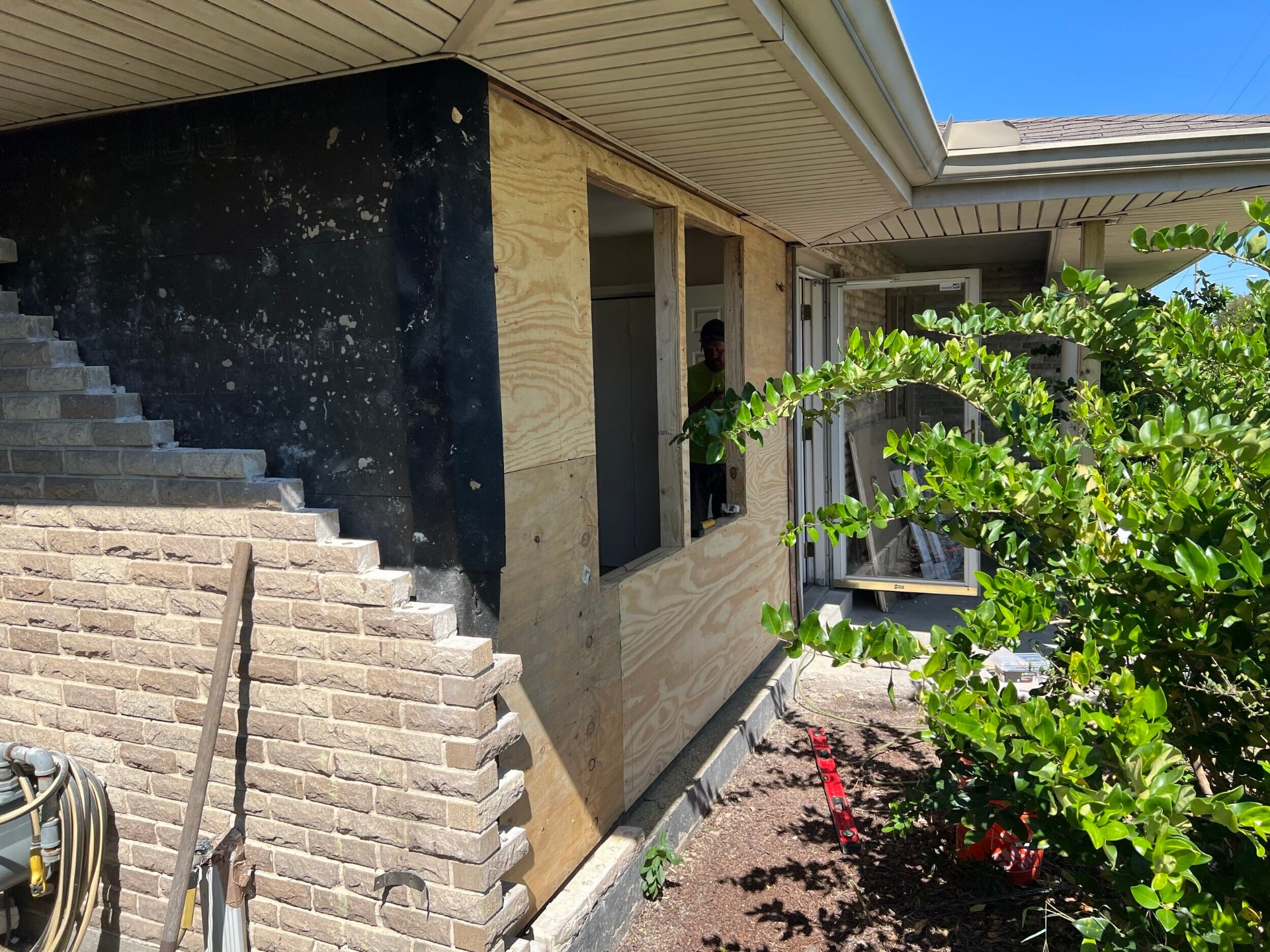 Exterior view of the rebuilt Gretna wall with plywood sheathing, new window rough opening, and prep for brick veneer