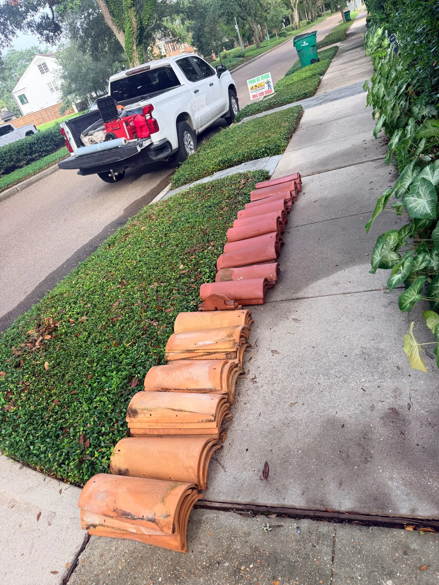 Sourced replacement terra cotta barrel roof tiles staged on the sidewalk beside a Cajun Home Services truck in Metairie Louisiana